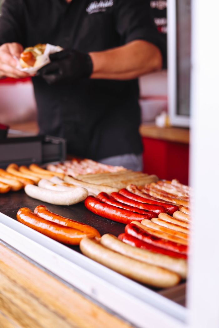 A street food vendor prepares mouthwatering grilled sausages at a market.